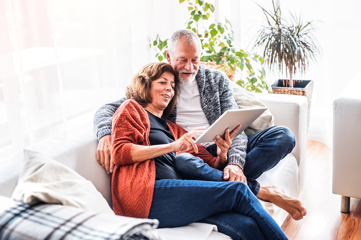 Middle aged couple on couch looking at tablet.